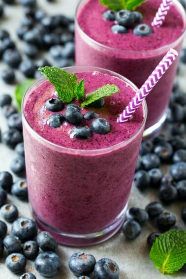 Blueberry smoothie in a glass with a straw.