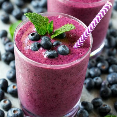 Blueberry smoothie in a glass with a straw.