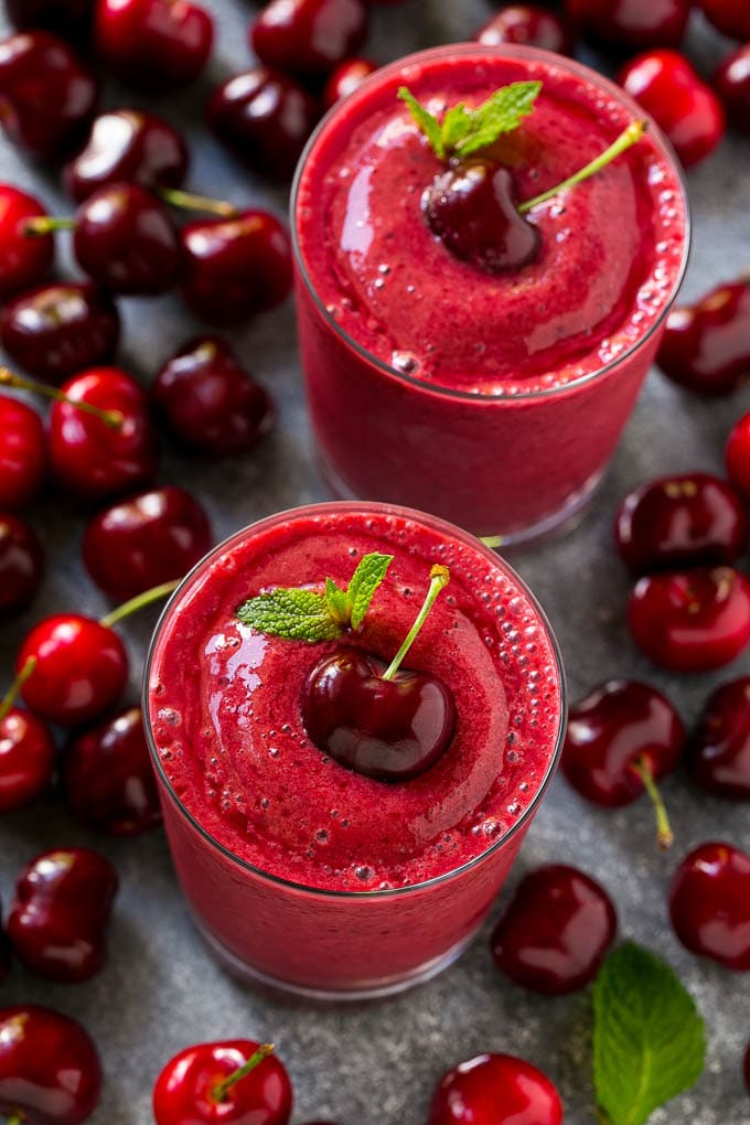 Cherry smoothie surrounded by fresh cherries.