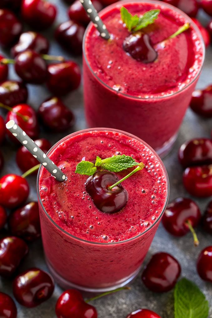 Two cherry smoothies topped with fresh cherries.