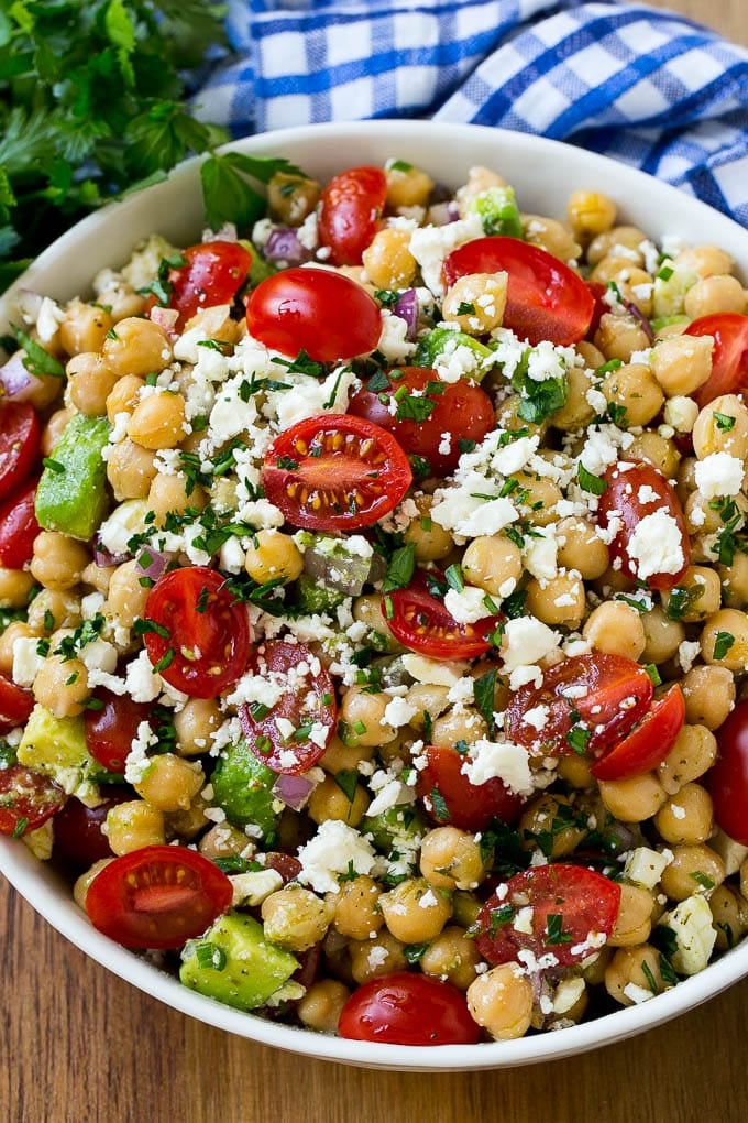Chickpea salad with tomatoes, cucumber, avocado and chives, tossed in dressing and topped with feta cheese.