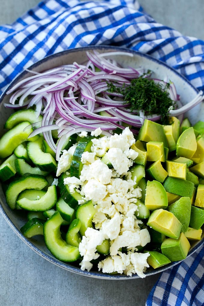 Cucumbers, feta, avocado and red onion in a bowl.