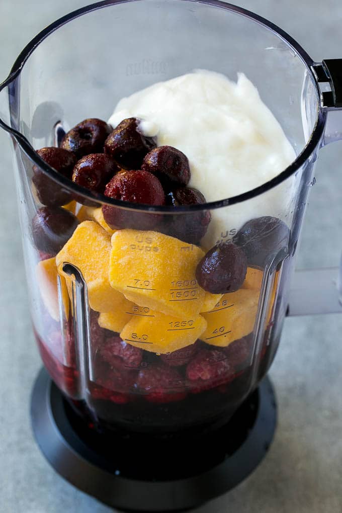 A blender full of frozen fruit, juice and yogurt.