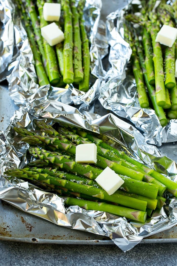 Raw asparagus stalks topped with butter and seasonings.