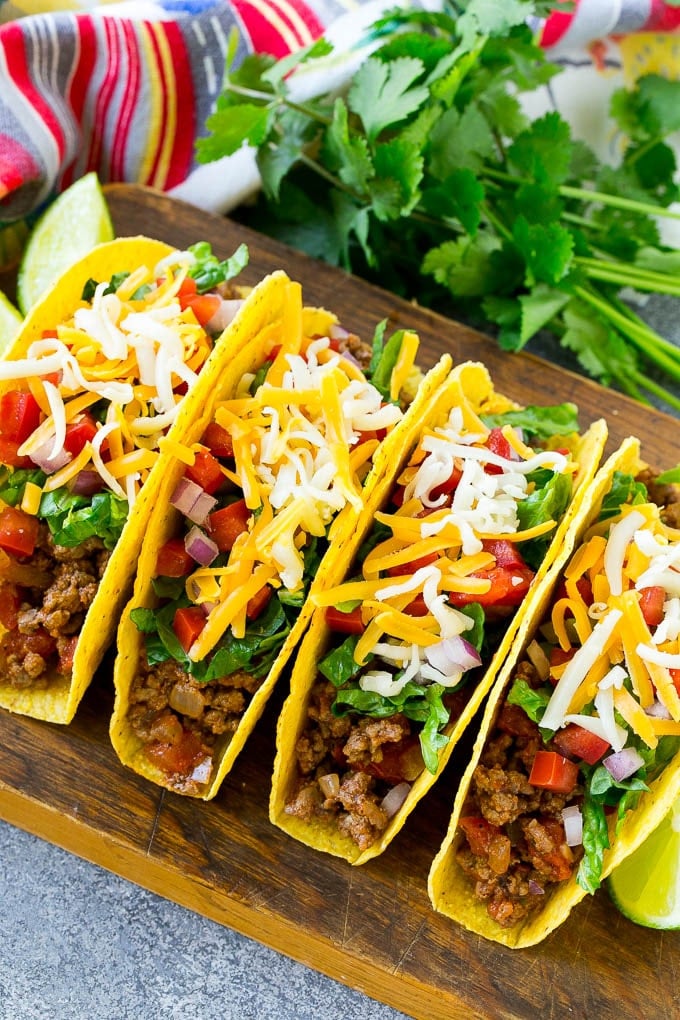 Crispy ground beef tacos with an assortment of toppings like lettuce, tomato and shredded cheese.