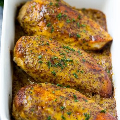 Baked honey mustard chicken garnished with chopped parsley.