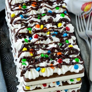 An ice cream sandwich cake with layers of the sandwiches, whipped topping and chocolate candy.
