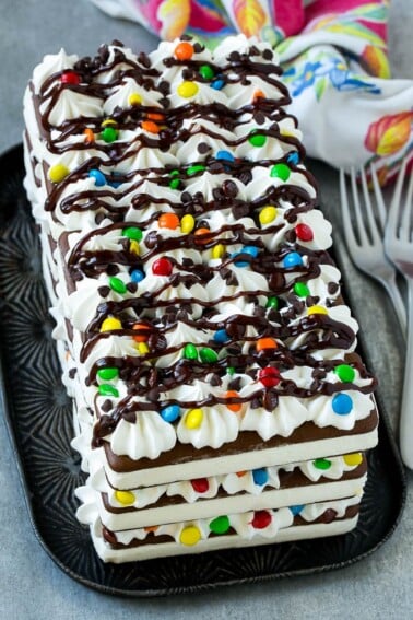 An ice cream sandwich cake with layers of the sandwiches, whipped topping and chocolate candy.