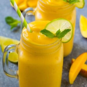 Mango smoothie in a mug topped with a slice of lime and mint sprig.