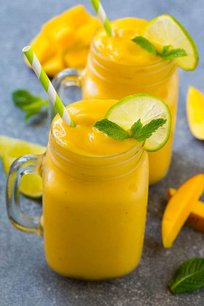 Mango smoothie in a mug topped with a slice of lime and mint sprig.