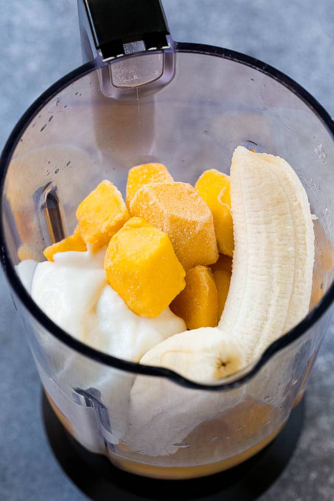 Frozen mango, banana, yogurt and juice in a blender.