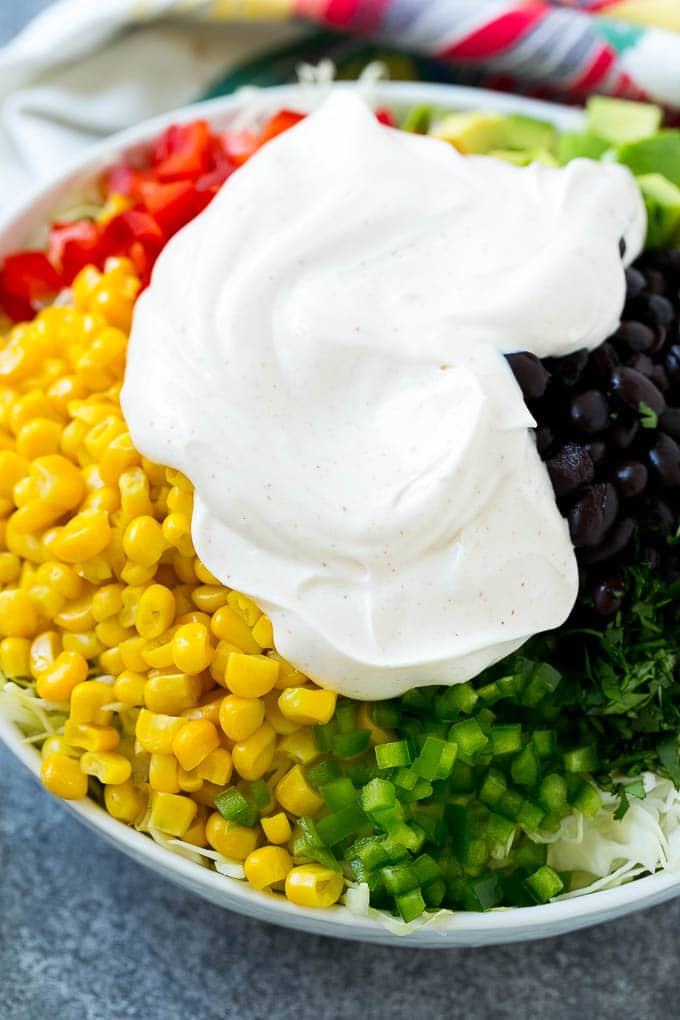 A bowl of cabbage and vegetables topped with Mexican coleslaw dressing.