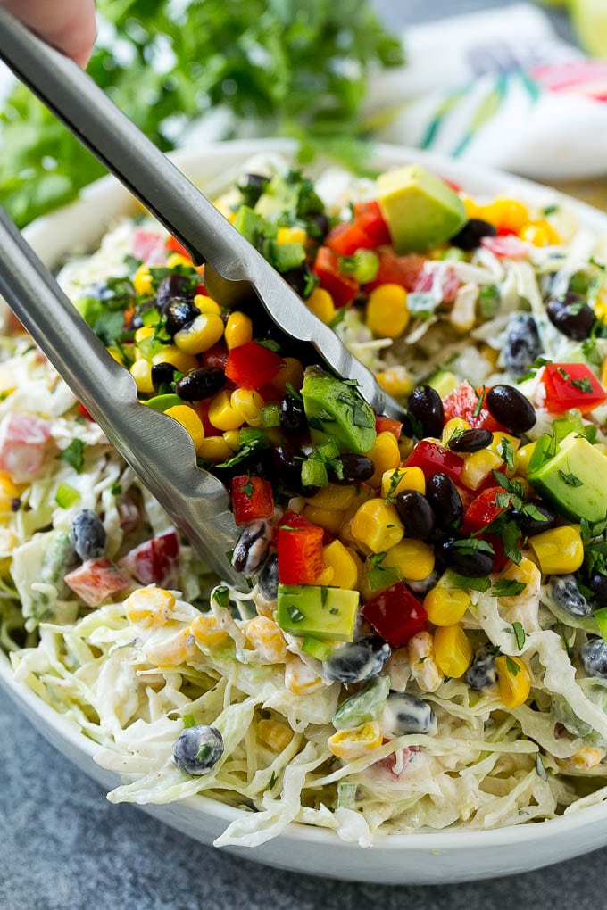 A bowl of Mexican coleslaw with salad tongs in it.