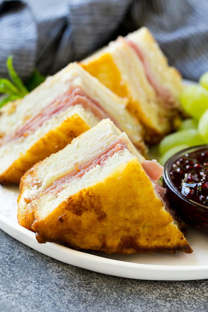 Wedges of Monte Cristo sandwiches topped with powdered sugar and served with raspberry jam.