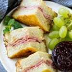 A plate of Monte Cristo sandwich with fresh fruit and raspberry jam for dipping.