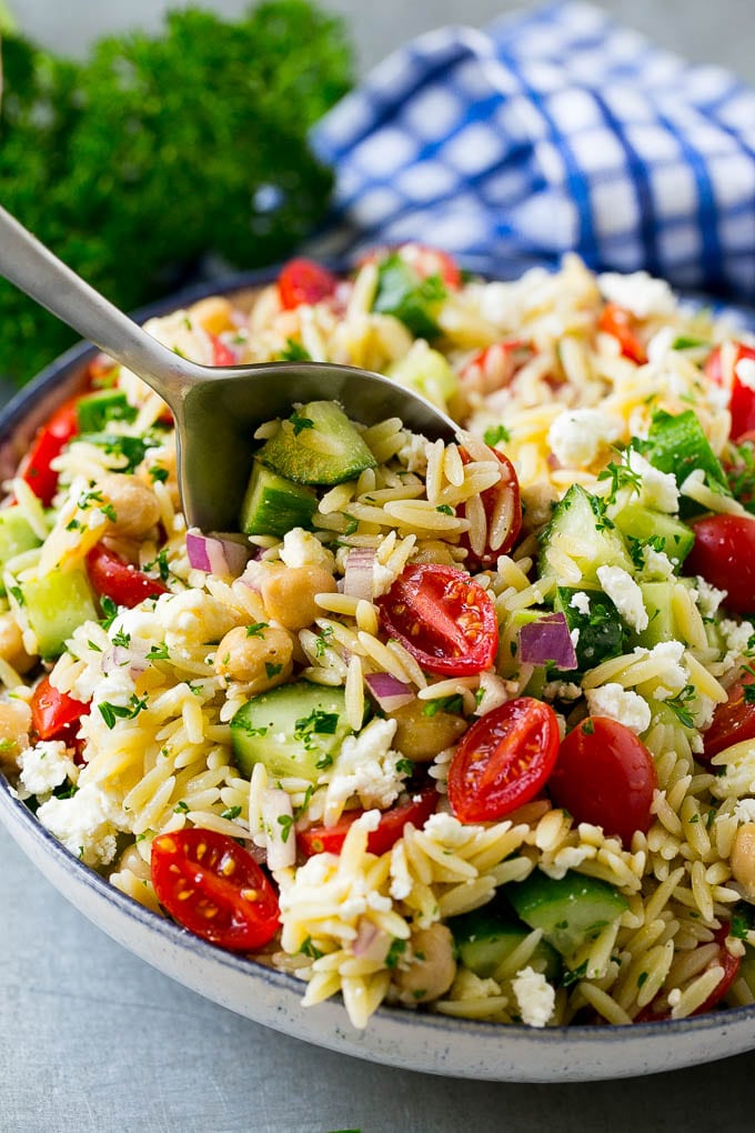 Orzo pasta salad with a serving spoon in the bowl.