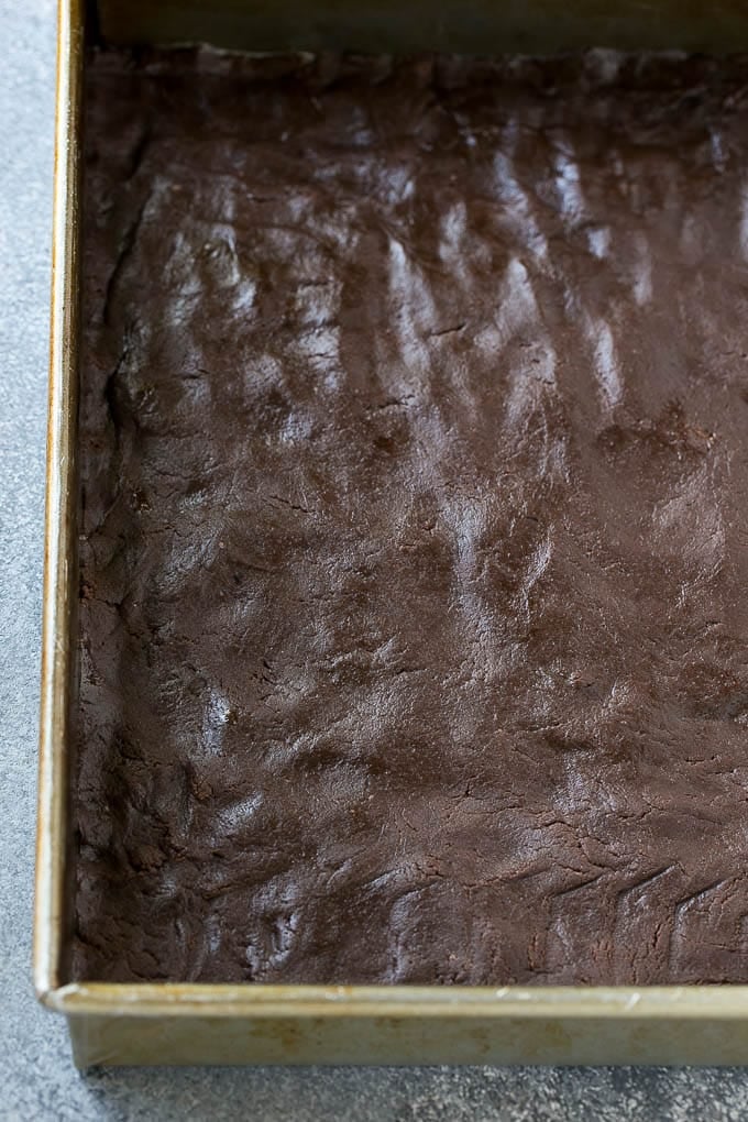 Chocolate cake crust pressed into a baking pan for a chocolate gooey butter cake.