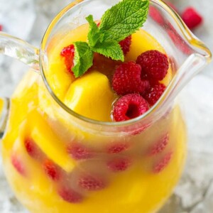 A pitcher of pineapple punch with fresh pineapple, raspberries and mint.