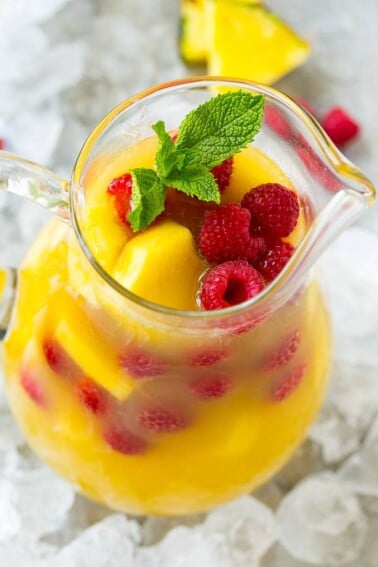 A pitcher of pineapple punch with fresh pineapple, raspberries and mint.