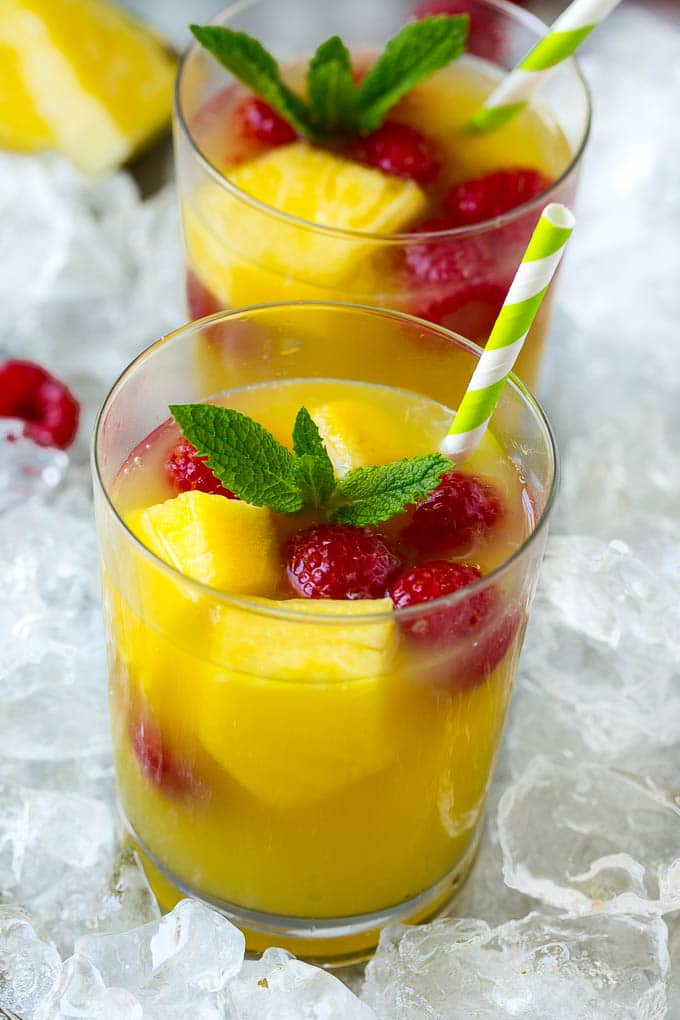 Glasses of pineapple punch with fresh pineapple and raspberries.