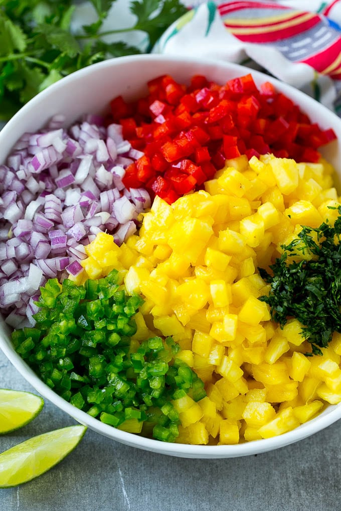 A bowl of pineapple, jalapeno, red onion, red bell pepper and cilantro.