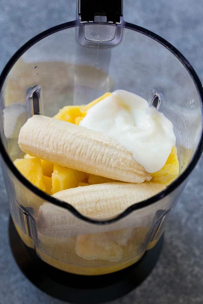 Frozen pineapple, pineapple juice, banana and yogurt in a blender.