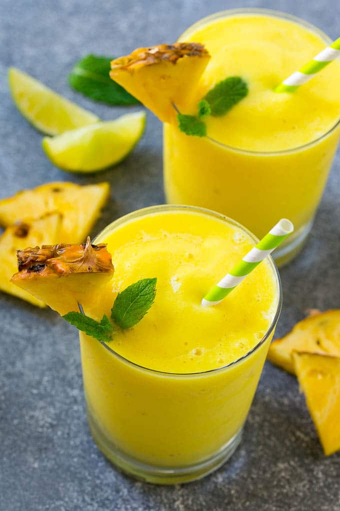 Glasses of blended pineapple smoothie with mint garnish.