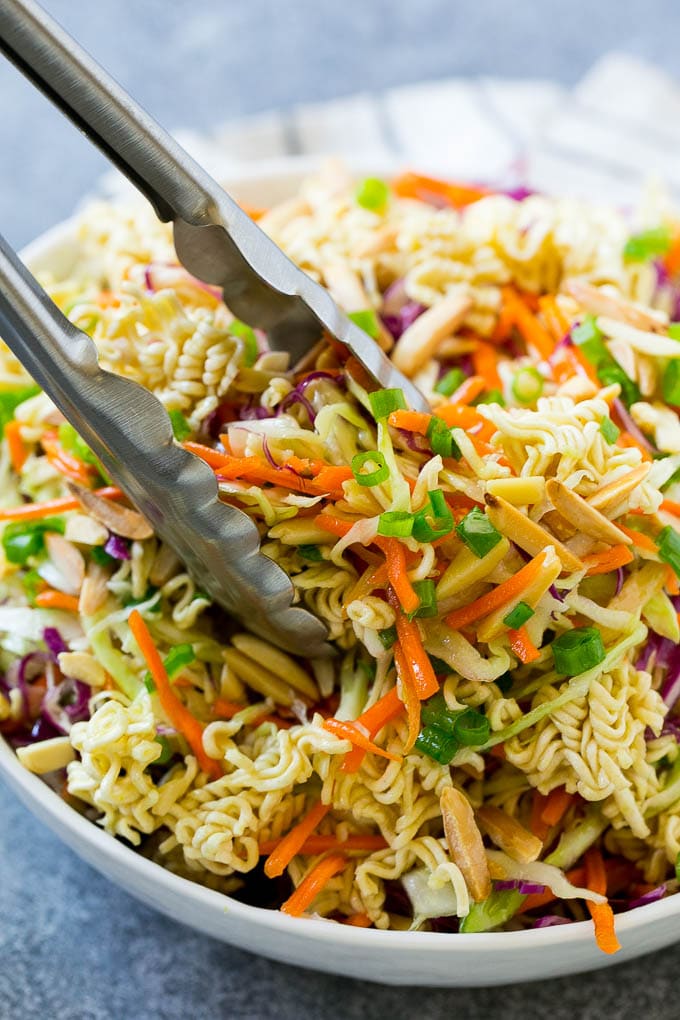 Ramen noodle salad with tongs scooping it out.