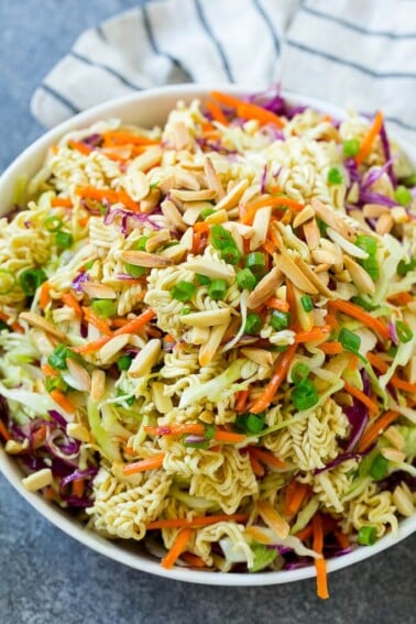 A bowl of ramen noodle salad with cabbage, noodles, green onions and almonds.