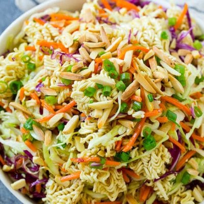 A bowl of ramen noodle salad with cabbage, noodles, green onions and almonds.