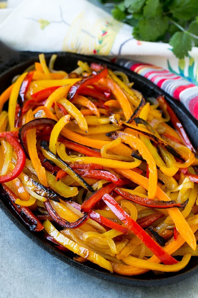 Blackened bell peppers and onions in a pan.