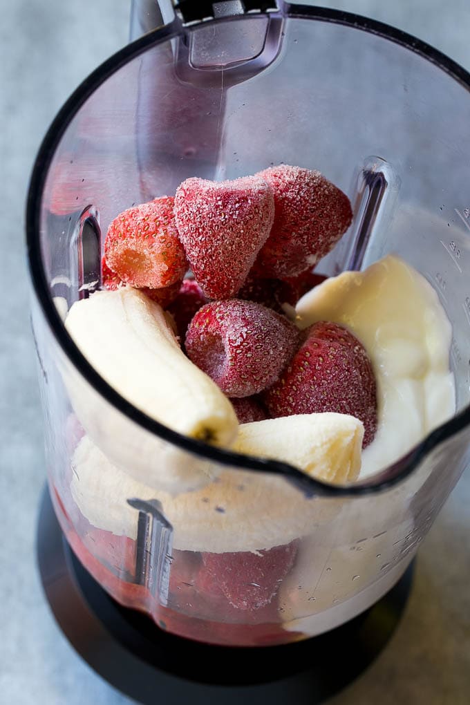 Frozen strawberries, apple juice, banana and yogurt in a blender.