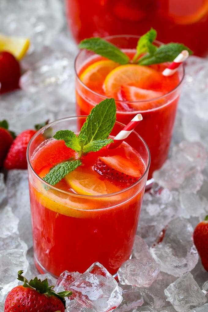 Cups of homemade strawberry lemonade garnished with mint sprigs and lemon slices.