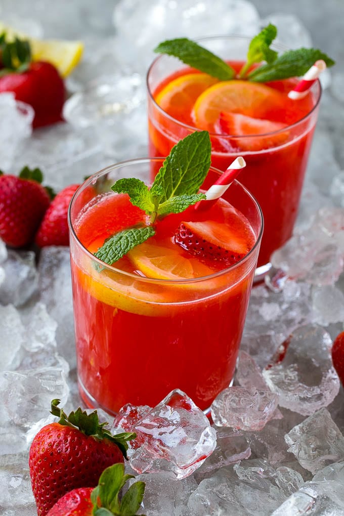 Glasses of strawberry lemonade in ice, garnished with fresh strawberries and lemon slices.