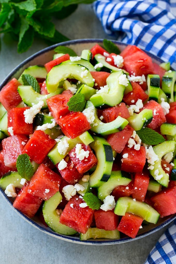 A bowl of watermelon feta salad with sliced cucumbers and mint leaves.