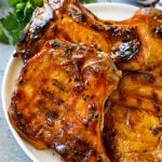 BBQ pork chops are bone in pork chops that have been grilled and topped with barbecue sauce.