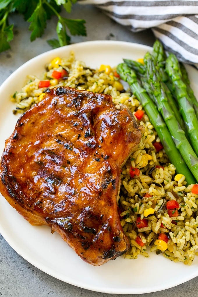 Grilled BBQ pork chops served over rice pilaf with a side of asparagus.