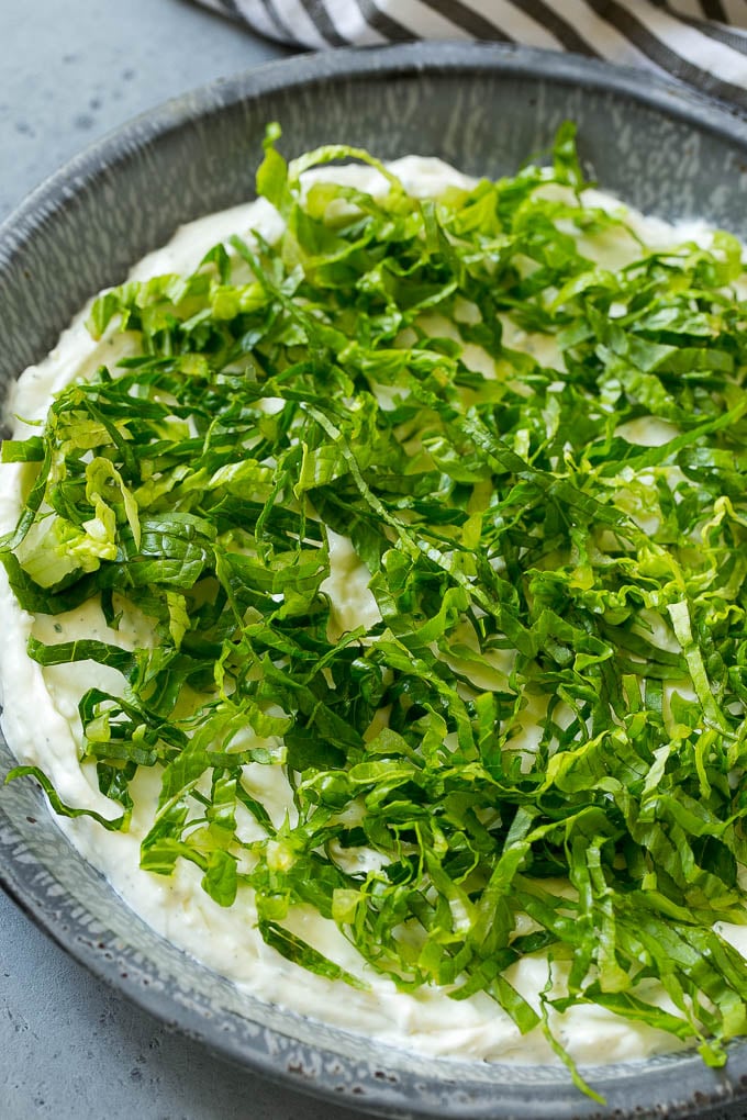 Shredded romaine lettuce over creamy ranch dip.