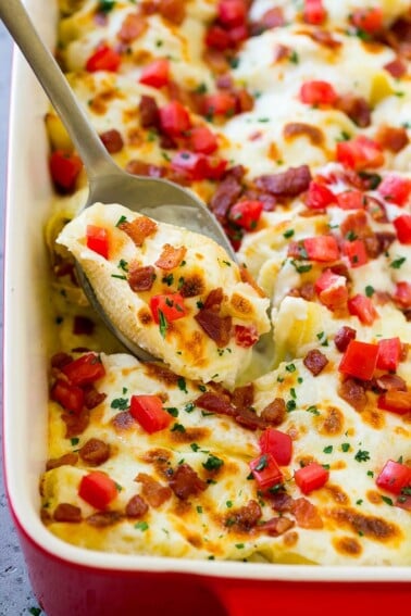 Chicken alfredo stuffed shells topped with bacon, tomatoes and parsley.