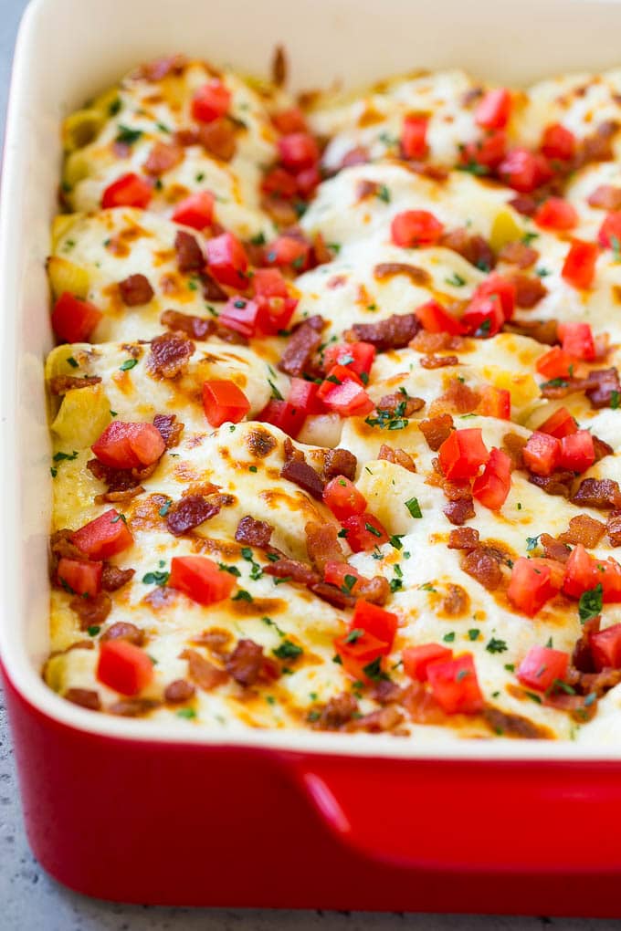 A baking dish of chicken alfredo stuffed shells topped with melted cheese.