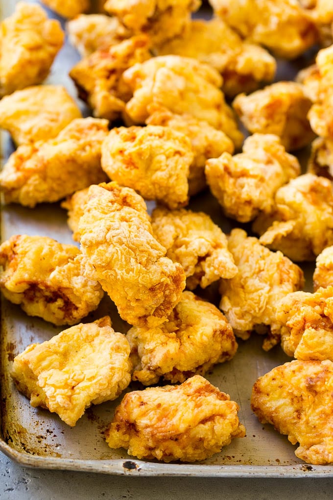 Fried pieces of chicken thighs on a sheet pan.