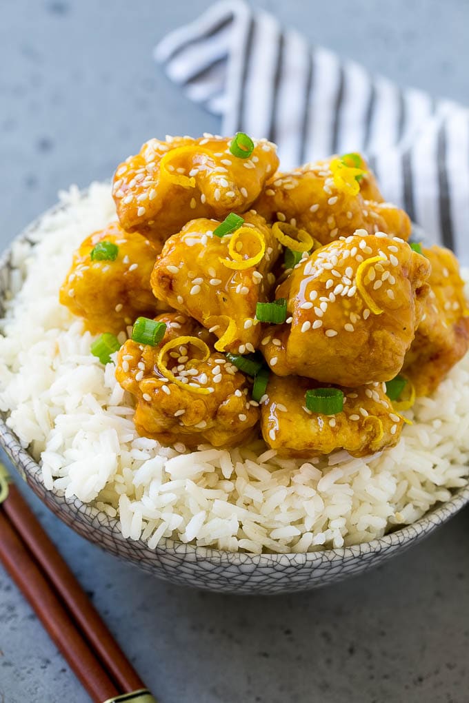 Chinese lemon chicken served over rice with chopsticks.