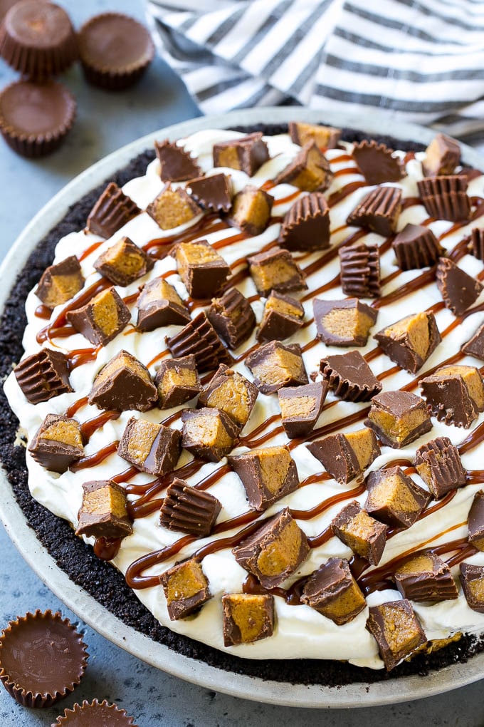 A peanut butter pie with cookie crust, peanut butter filling, whipped cream topping and chopped peanut butter cups.
