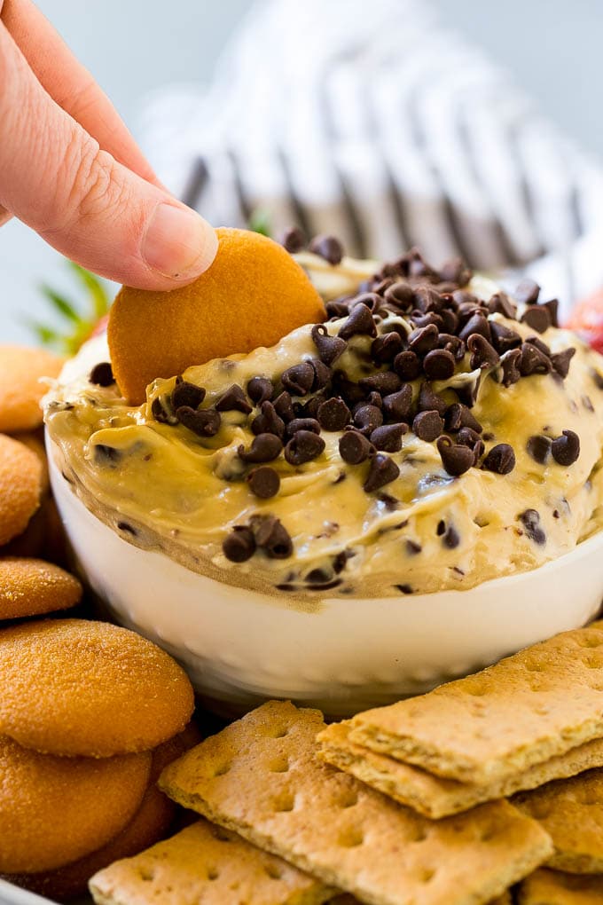 A cookie scooping into a bowl of cookie dough dip.