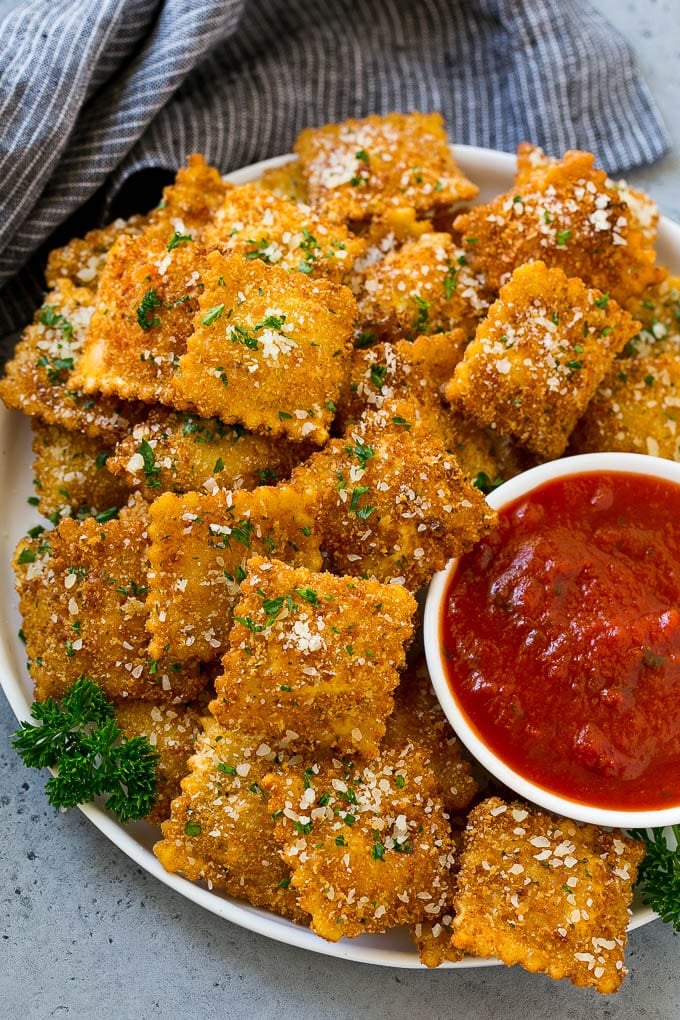 A plate of toasted ravioli with a side of marinara sauce for dipping.