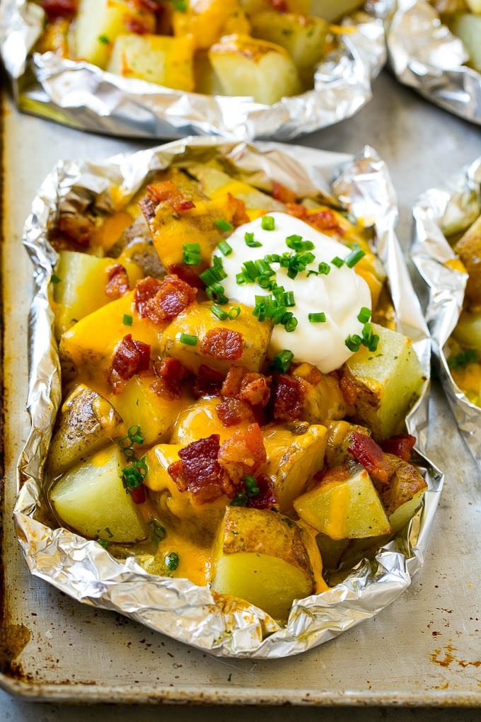 Grilled potatoes in foil with melted cheese, bacon and sour cream.