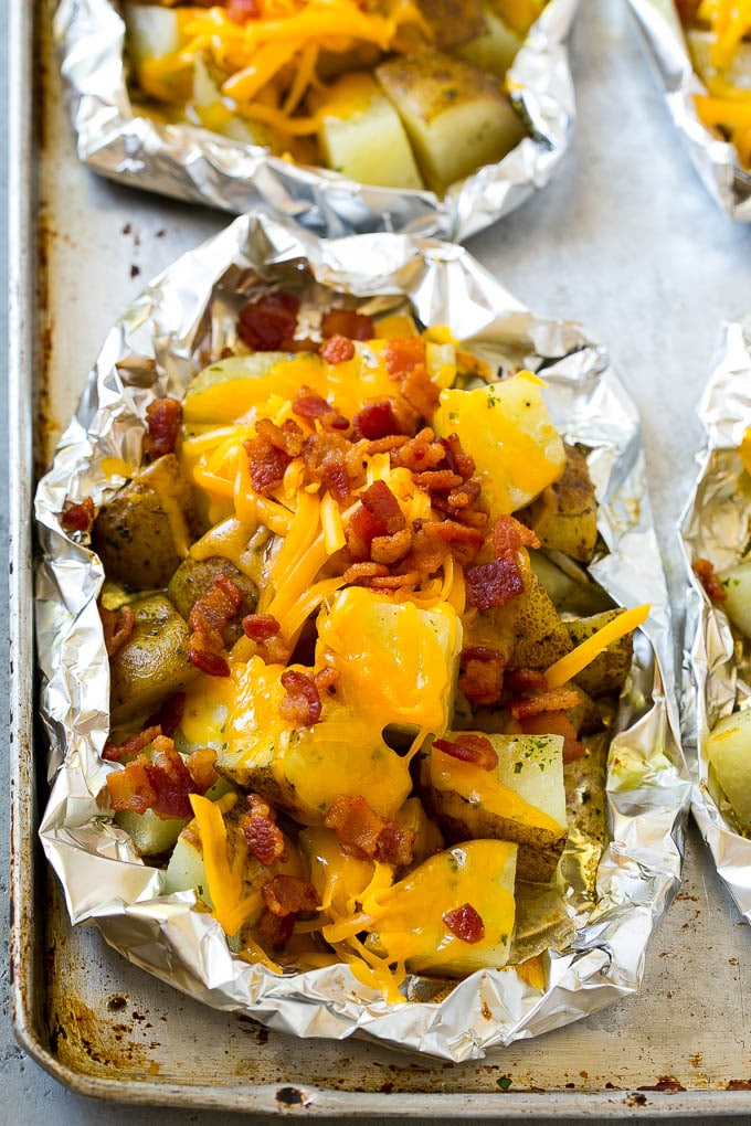 Potatoes topped with shredded cheese and bacon in foil packets.