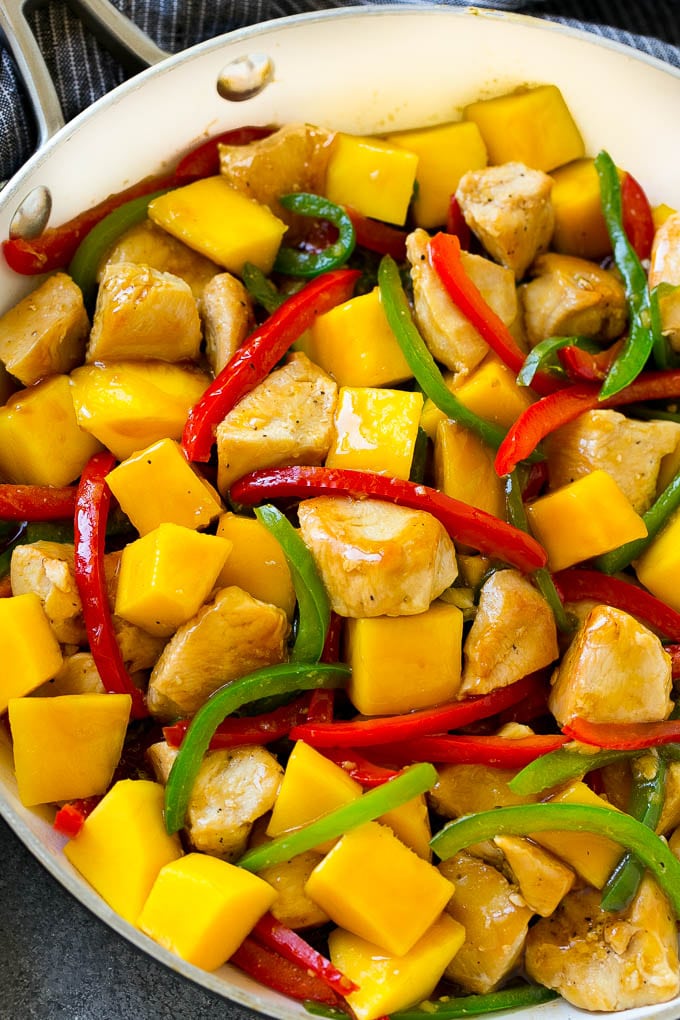 Mango chicken in a pan with red and green peppers.