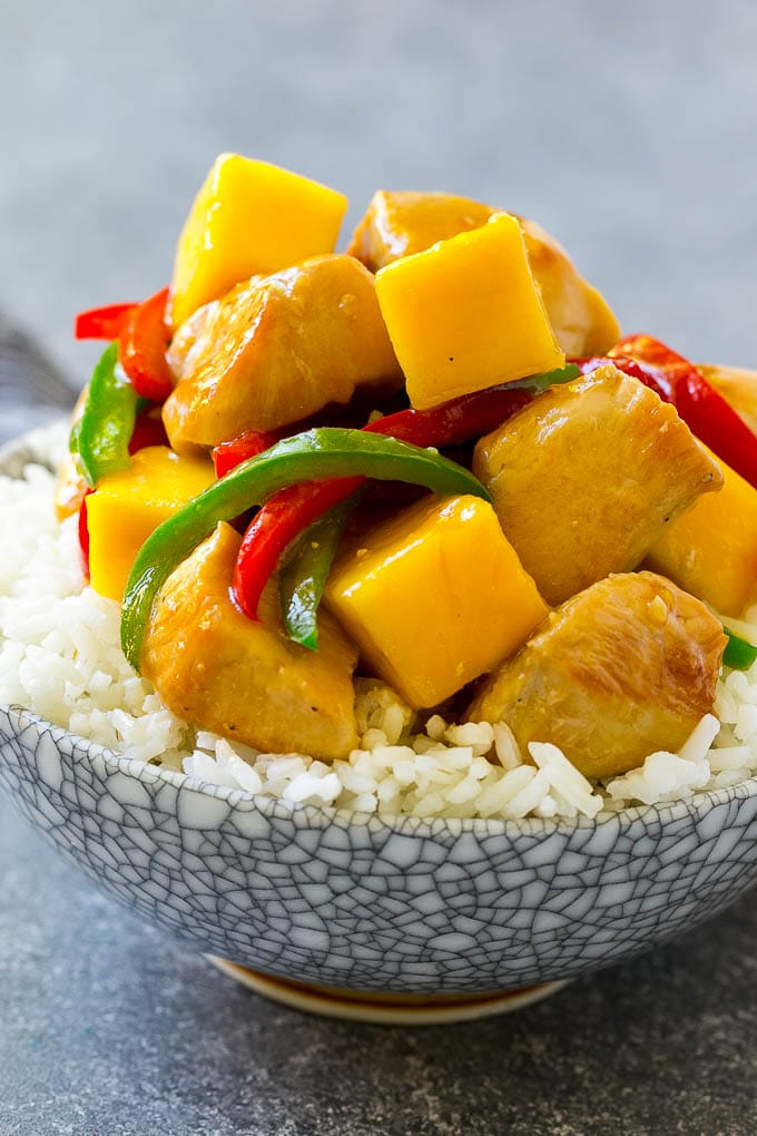 A bowl of mango chicken served over rice.