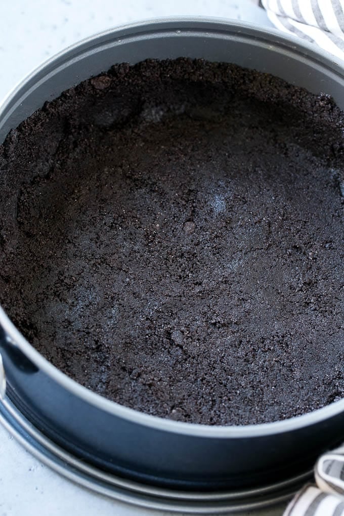 An oreo cookie crust in a springform pan.